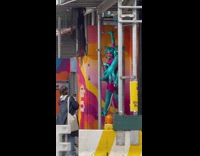 Collab WINY - Person in Alien Costume Holds on Scaffolding