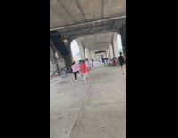 Women follow zumba dance instructor in class under freeway bridge 