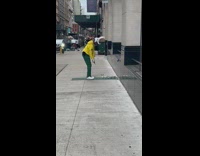 Man plays golf on busy street side of building
