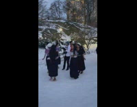 Guy filming people in cultural clothing walking in circles at park