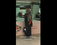Man with a lot of cross pins on his clothes stands with briefcase in subway station