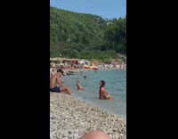 Woman in bikini kneels and poses at the beach shore