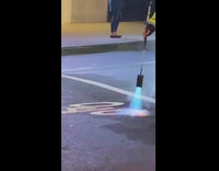 Street worker in green vest blowtorches bike sign onto cement