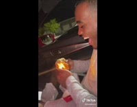Guy using lighter on chicken sandwich in car 
