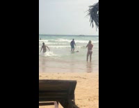 Lady Records Man Practice with Surfboard on Beach