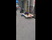 Guy sleeping on mattress on bed frame on sidewalk