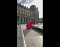 Woman long red dress adjusts gown to the wind