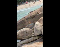 Woman bend over pose on beach rocks