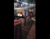 Man singing and standing on dining table on street 