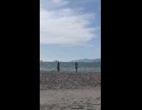 Two women wears a lei and dances at the beach