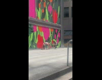 Woman bends her body near the building with flower drawings