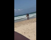 Man with opened polo and sunglasses poses at the beach