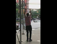 Guy red white striped shirt does pull ups on metal bar on building frame