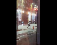 Guy practices golfing on street at night 