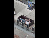 Couple lays on a sidewalk couch and touches each other 