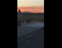 Girl blue shorts hula hoop tricks sunset