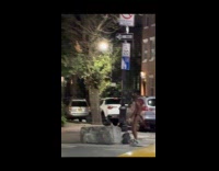 Man wearing devil costume and thong dancing on street