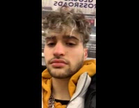 Old man wears Perry the Platypus beanie and bright purple jacket on subway train 