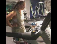 Woman on treadmill at the gym, another woman runs on the treadmill next to her and they try to outrun each other