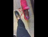 man with black shoe compares foot to red tennis shoe