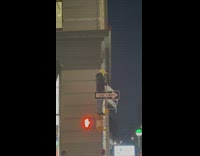 Guy wearing shrek mask stands on pedestrian light 