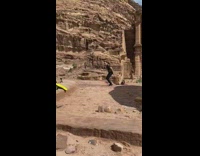 Guy jumps picture Petra stone building 