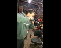 Guy sawblades a can of beer and shotguns it inside workshop