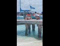 Woman in bikini and a hat lie down on the dock