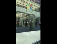 Man dressed up as a wizard in green cloak walks in front of the Microsoft store