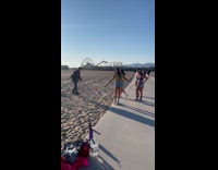 Four women shuffle dance on the beach walkway