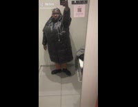 Girl in fitting room with huge black puffer jacket