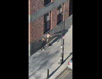 Lady Prompts Fashionable Friend How to Pose on Corner Wall