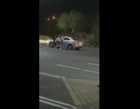 Two girls dance beside grey car night