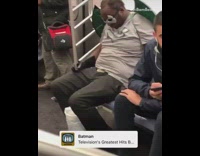 Man dresses up in Batman costume and takes walkie talkie out from pants on subway