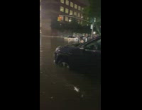Guy walks in flooded street with water up to knees 
