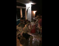 Shirtless guy drinks out of red cooler and gets sprayed by friends shotgun beers