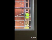 Guy inside living room blows whistle at construction worker