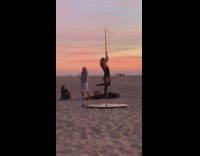 Girl dances and swings around pole beach 