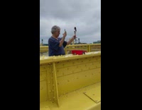 Man takes a picture of a doll next to a giant pickle