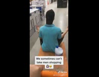 Girl pushes orange platform cart with guy 