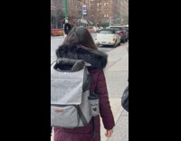 Woman walks with black goose in backpack 