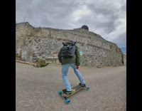Guy skateboards down windy road with drone