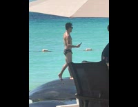 Man in his underwear and sunglasses is taking a selfie at the beach