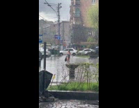 Woman wearing sleeveless shirt soaked in rain crossing street 