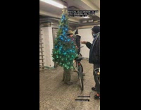 Guy wearing a christmas tree talking to another guy at station