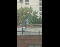 Guy practices his lasso skills on roof top of apartment with a stool