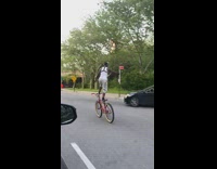 Guy stands on bicycle singing while he rides