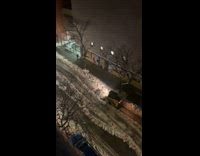 Yellow snowplow dumps snow middle of street 