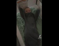 Excited baby waves arms around in bed 