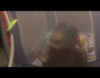 Little toddler girl rubs her face against mesh wall of playpen